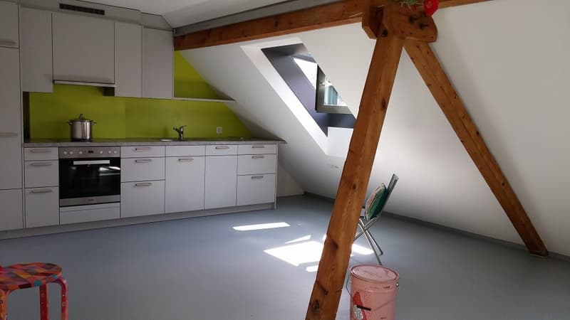 Attic kitchen with gray cabinets, green backsplash, wooden beams, and a skylight window