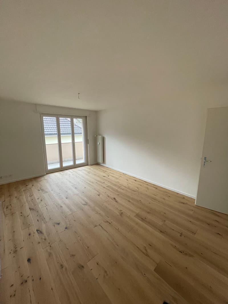 large empty room, white walls, glass sliding door, wooden floor