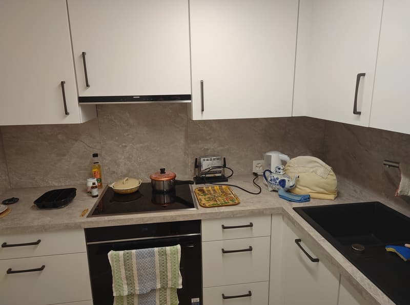 White kitchen cabinets, black oven, induction stove, grey countertops, kitchenware