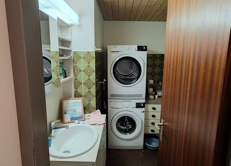 Laundry room with washing machine, dryer, sink, and shelves.