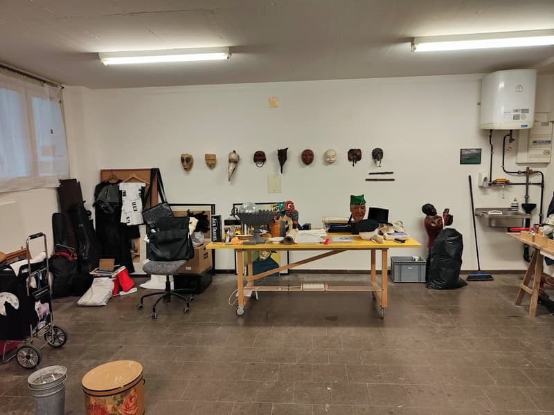 Empty room with desk, masks on wall, items scattered, and a water heater.