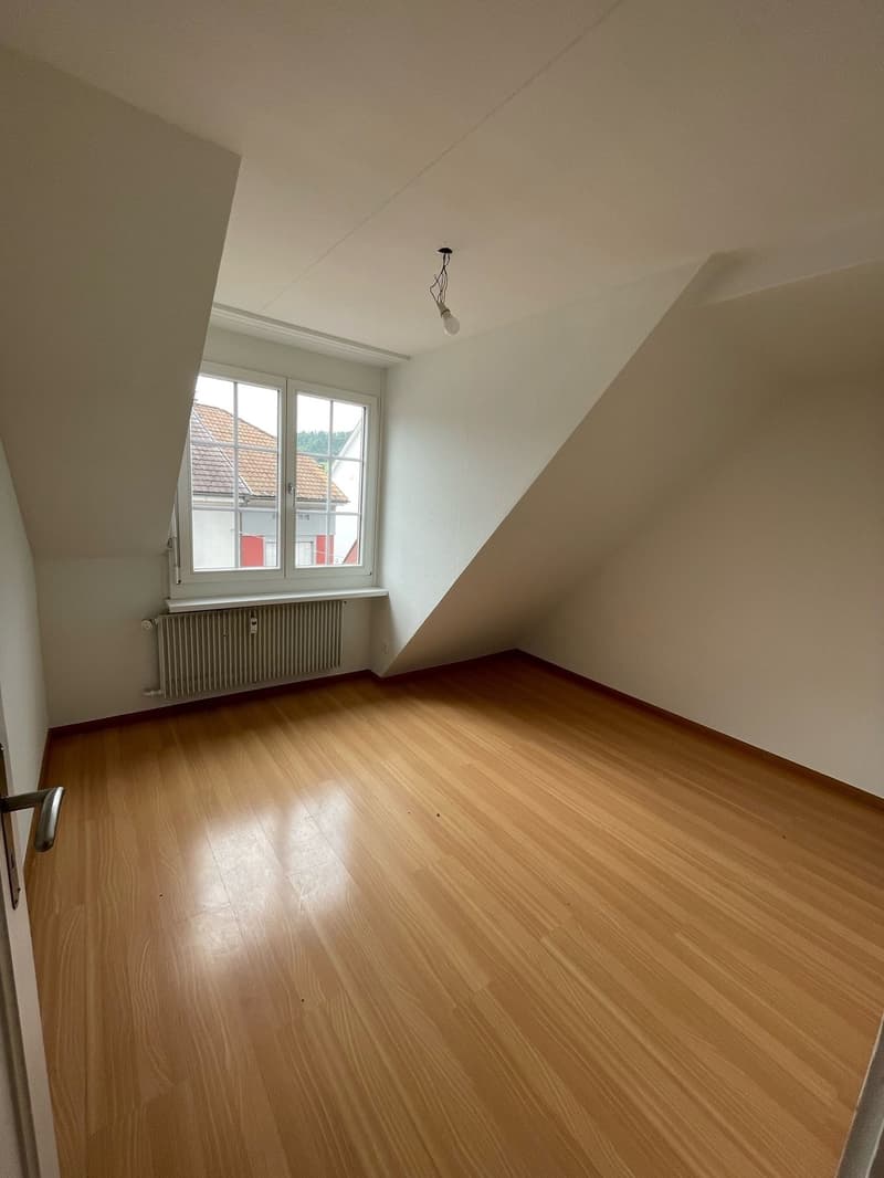Spacious room with hardwood flooring, white walls, and a single window providing natural light. The room appears to be empty, ready for furnishing and decorating.