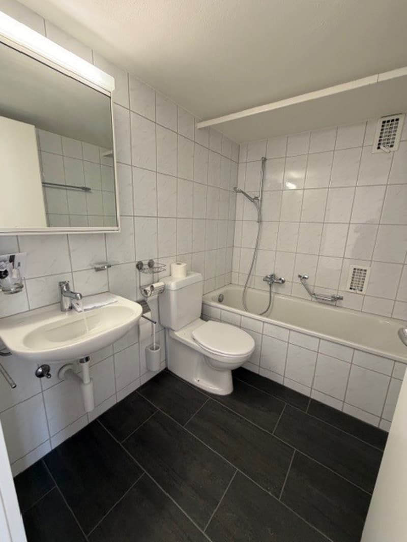 Bathroom with white tiles, white sink, white toilet, white bathtub, mirror, and shower