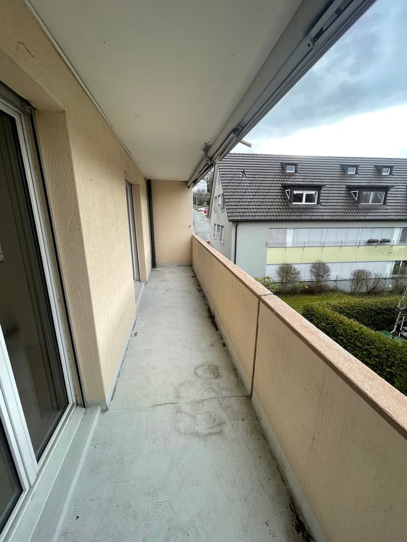 balcony, white floor, white railing, open sliding glass door, view of another house, overcast sky
