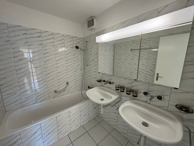 white tiles, bathtub, two sinks, mirror, shower
