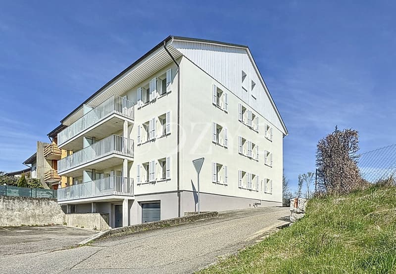 3-story apartment building, white exterior, balconies on each floor, paved driveway, grassy area around the building
