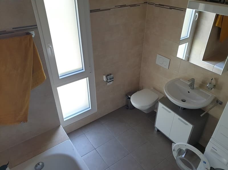 Bathroom with bathtub, toilet, sink, window, and towel