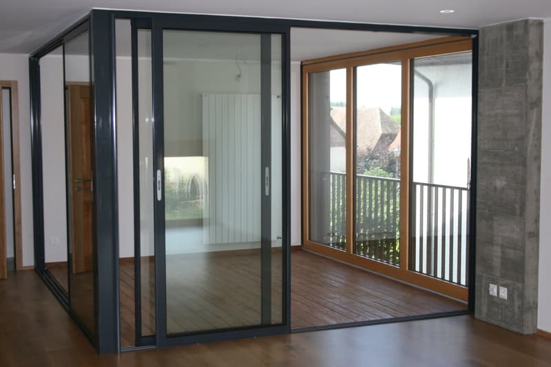 sliding glass doors, wooden floor, balcony with railings, white walls, white radiator