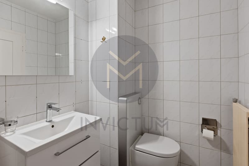 Salle de bain W.C. / a small bathroom with white tiles on the walls and a sink
