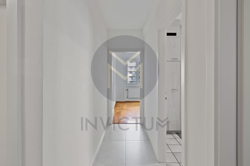 / a long narrow corridor with white walls and wood floors and a long hallway with a door to another room in a modern house