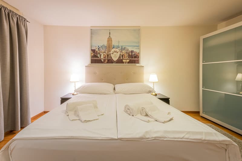 Double bed, 2 pillows, white linen, nightstands, lamps, picture frame, cabinet, curtains