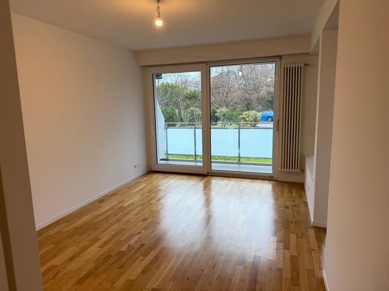 large sliding glass doors leading to balcony, hardwood floors, white walls, sliding wall, white electric outlet