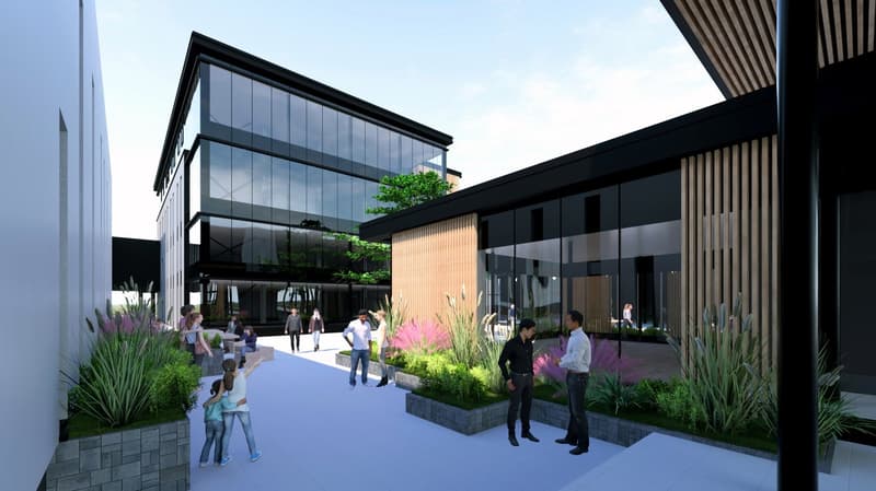 Exterior of a building with a glass facade, plants, and a large pathway, showcasing a community feel