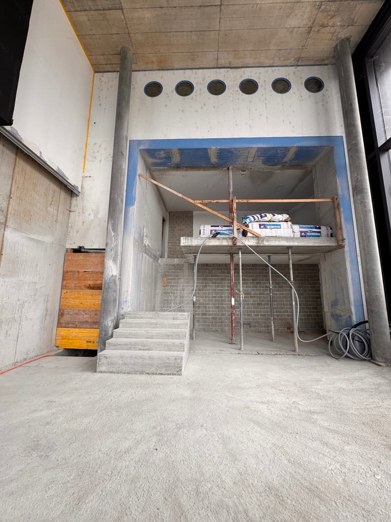 Construction site with unfinished structure, staircase, steel beams, and building materials