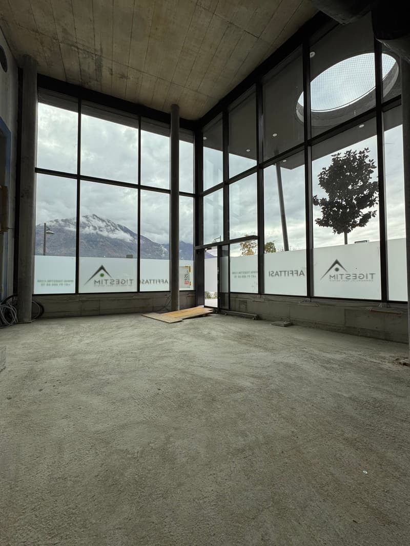 Empty room, concrete floor, large windows, view of mountains, exit door