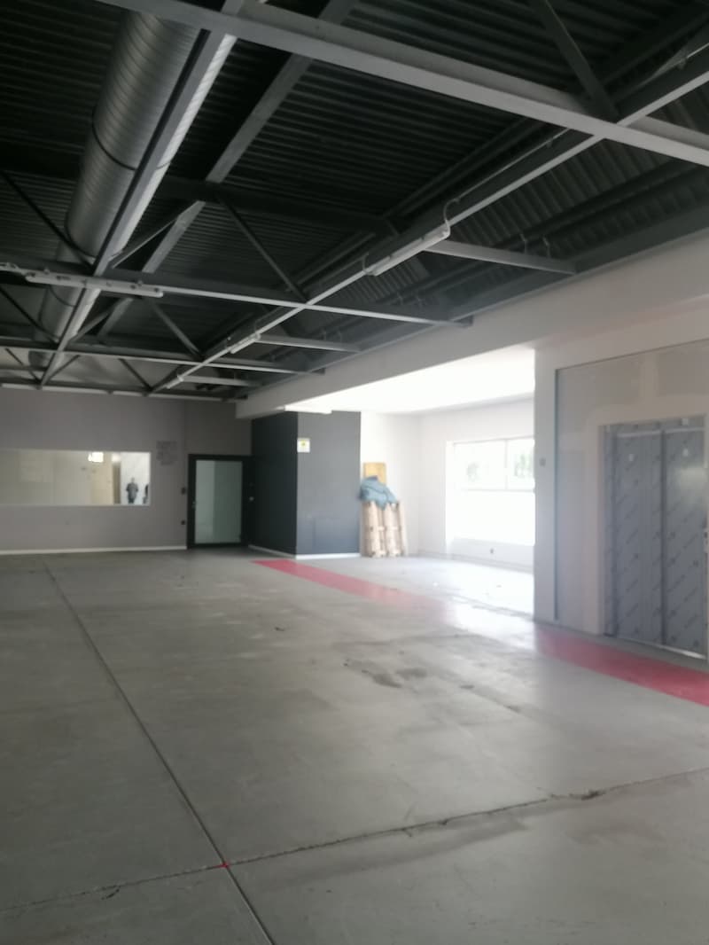 Empty parking lot with concrete floor, metal beams, and a red line on the floor.