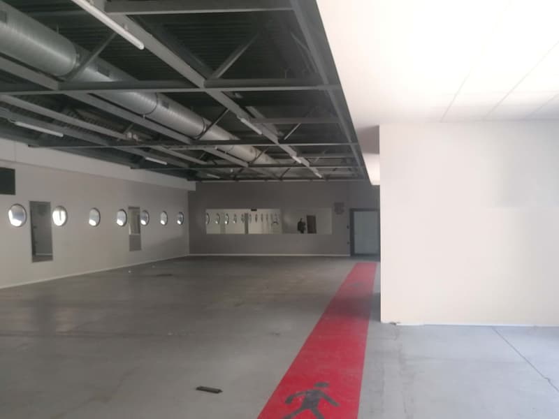 Empty parking lot, concrete floor, red line, metal beams, pipes, round mirrors, white walls, door