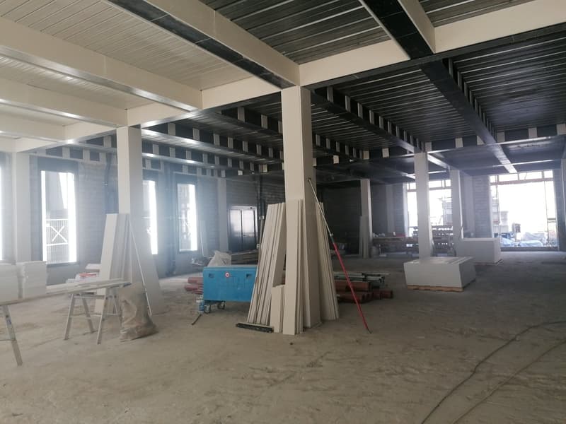 unfinished building, high ceiling, large windows, construction materials