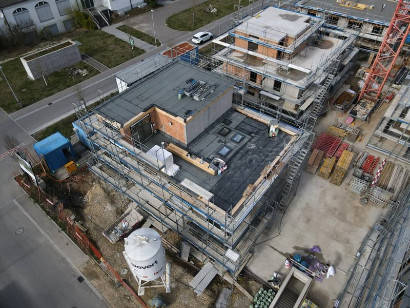 Aerial view of a construction site with multiple buildings under construction, scaffolding, and various construction materials and equipment.