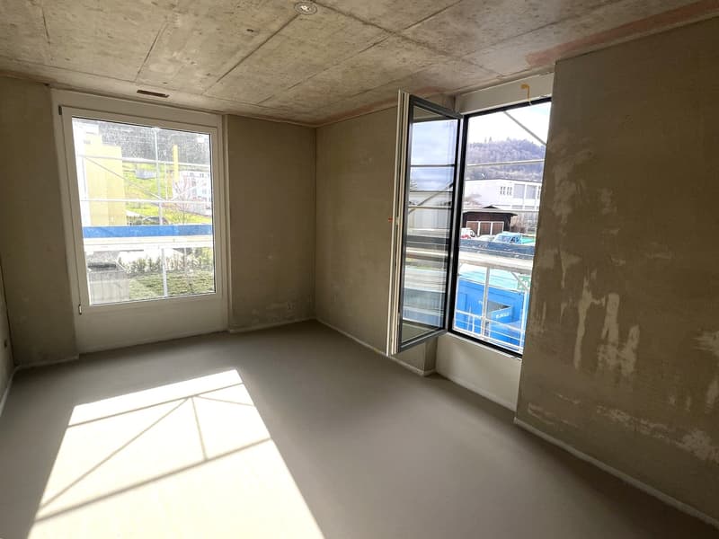 empty room, two windows, concrete floor, unfinished walls