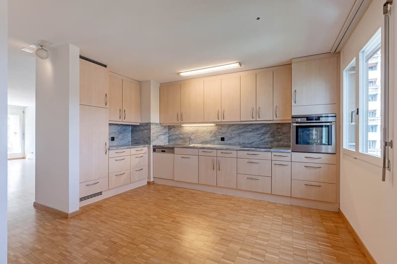 modern kitchen with wooden floors, white cabinets, granite countertops, built-in oven and dishwasher, large windows