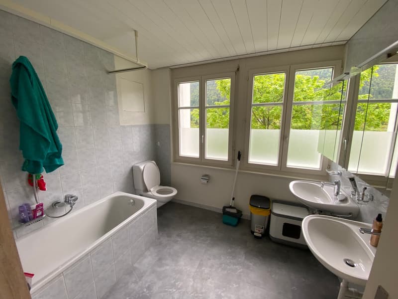 Bathroom with bathtub, toilet, two sinks, and windows with view