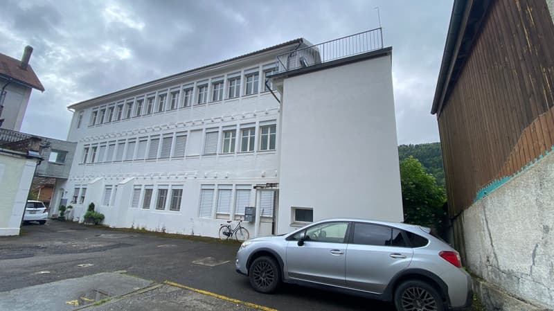 white building, multiple windows, balcony, car parked in front