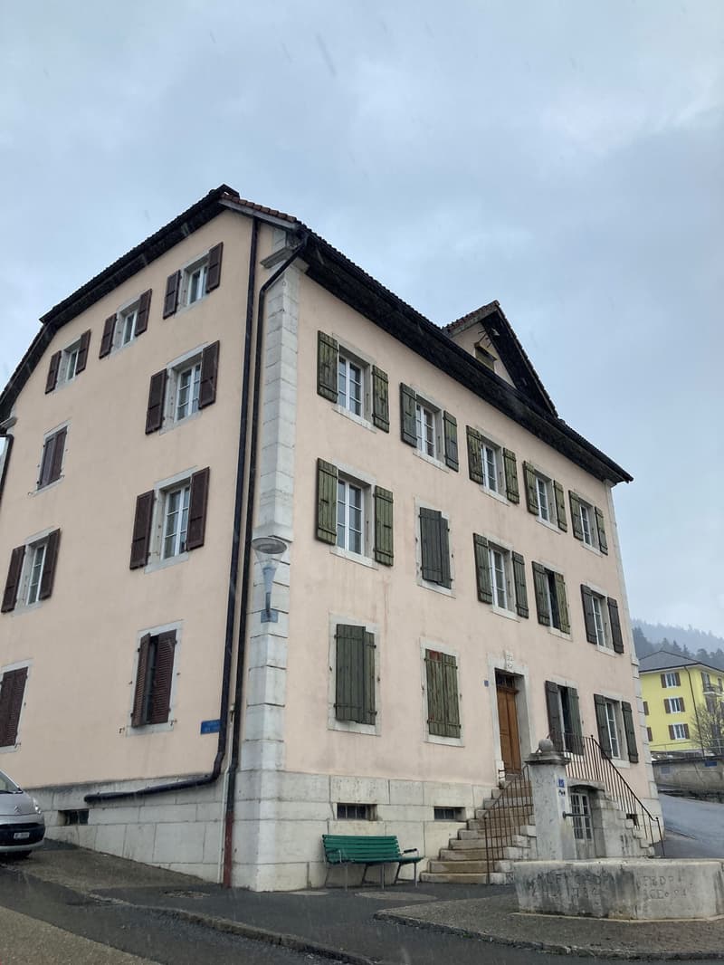 pink building, 3 floors, many windows, green shutters, door at base of building