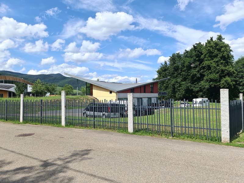 a parking lot near the building, metal fence, several cars parked