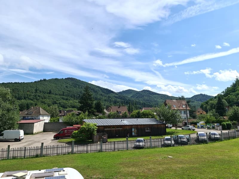 Exterior view of property, several parked cars, grassy lawn, mountains in the background