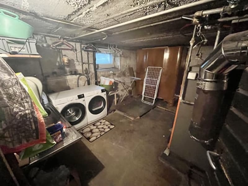 Cluttered basement with washing machine, dryer, and other household appliances and storage items