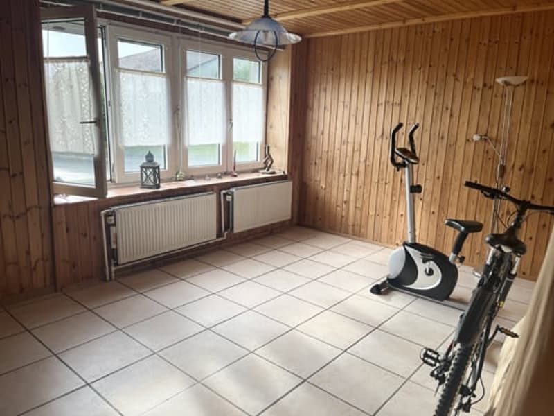Spacious room with wooden walls, large windows, tiled floor, exercise bike, and a washing machine