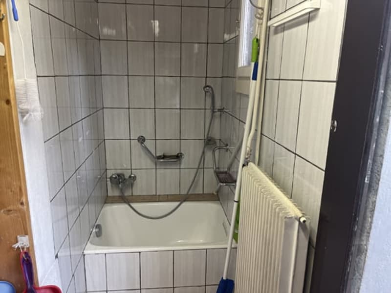 Tiled walls, bathtub, shower head, radiator