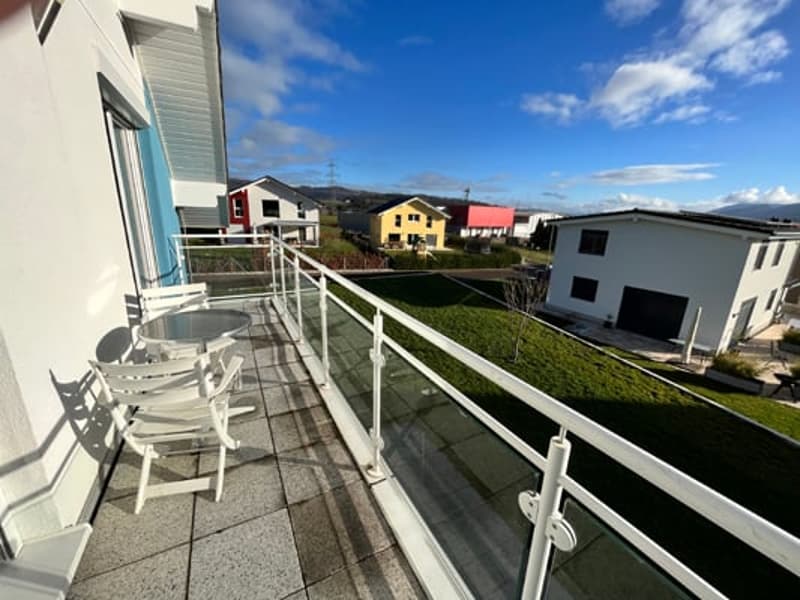 Balcony with outdoor furniture, overlooking a residential neighborhood with colorful houses and buildings