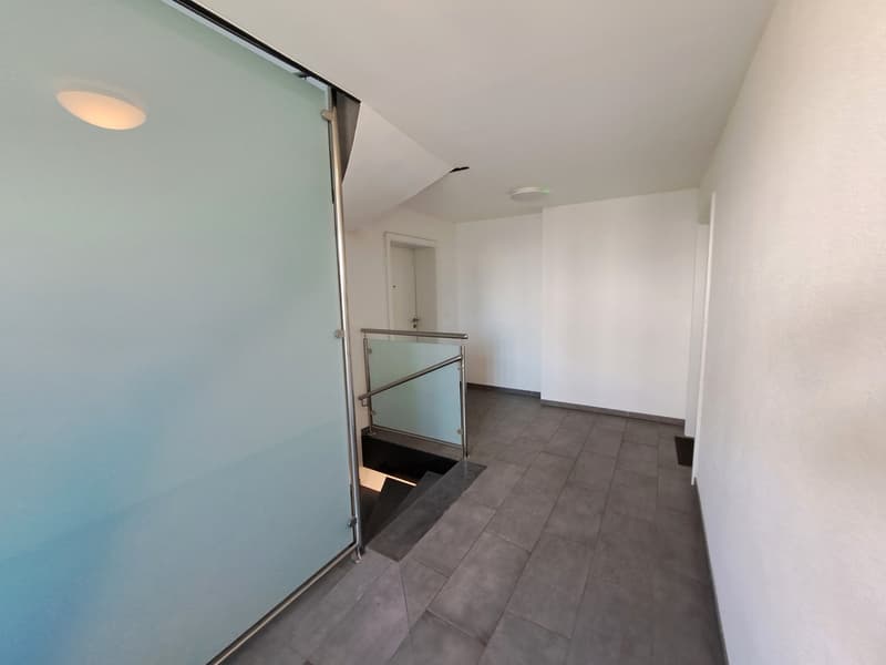 Hallway with glass sliding door, tile flooring, and recessed lighting