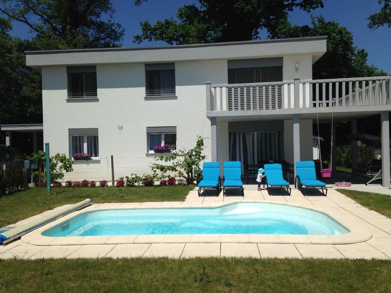 Modern white house with swimming pool and lounge chairs