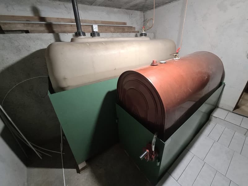 Storage room, 2 tanks, one white, one brown, tiled floor, concrete walls