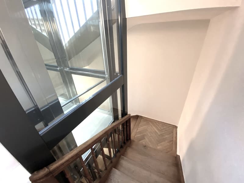 Wooden handrail on a glass-elevator side, wooden steps, raised ground floor