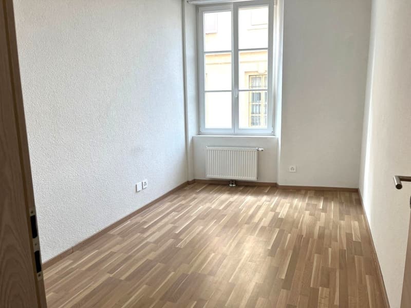 an empty room with white walls and wooden floor