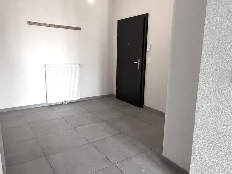 empty room with tiled floor, white walls, closed door, white radiator, power outlets