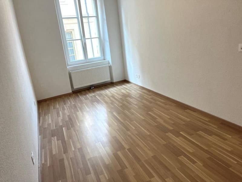 large room, wooden floor, white walls, radiator, windows, light