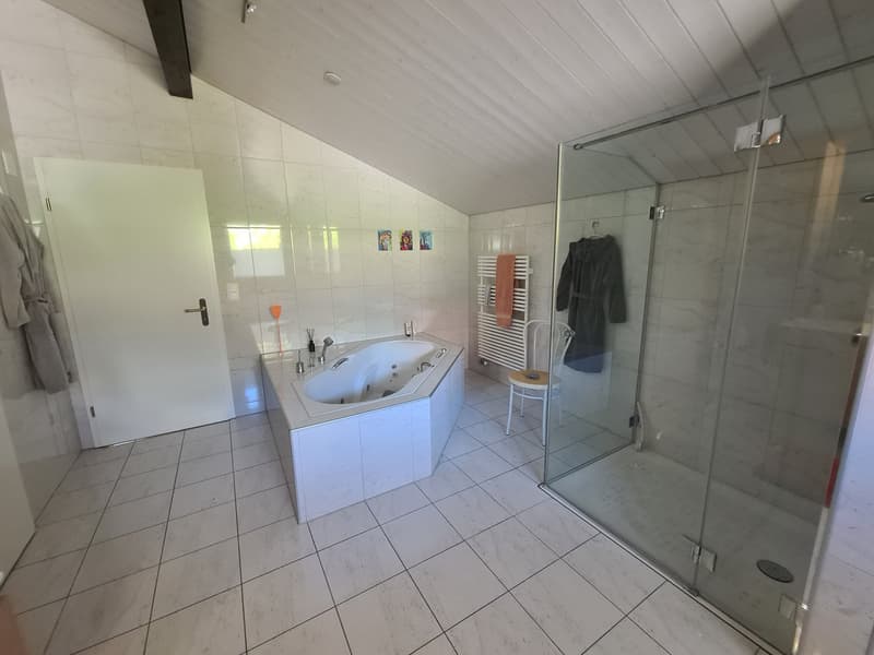 tiled floor, large bathtub, shower stall, towel rack, white walls, white ceiling, glass door, white door