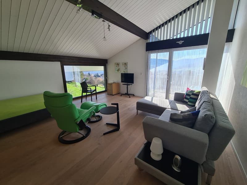 open space living room with wooden floor, couch, TV, chair, desk, lamps, window