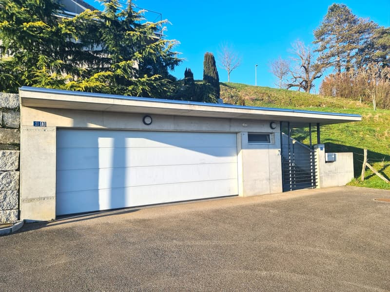 concrete structure, white garage door, adjacent staircase, adjacent stone wall