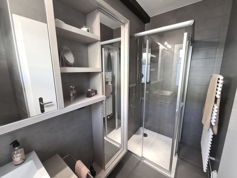 Contemporary design bathroom with glass shower, white walls, white sink, and towel holder.