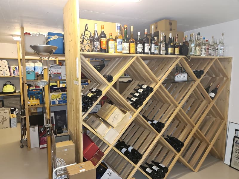 Wine rack, wooden structure, various wine bottles, boxes and other items.