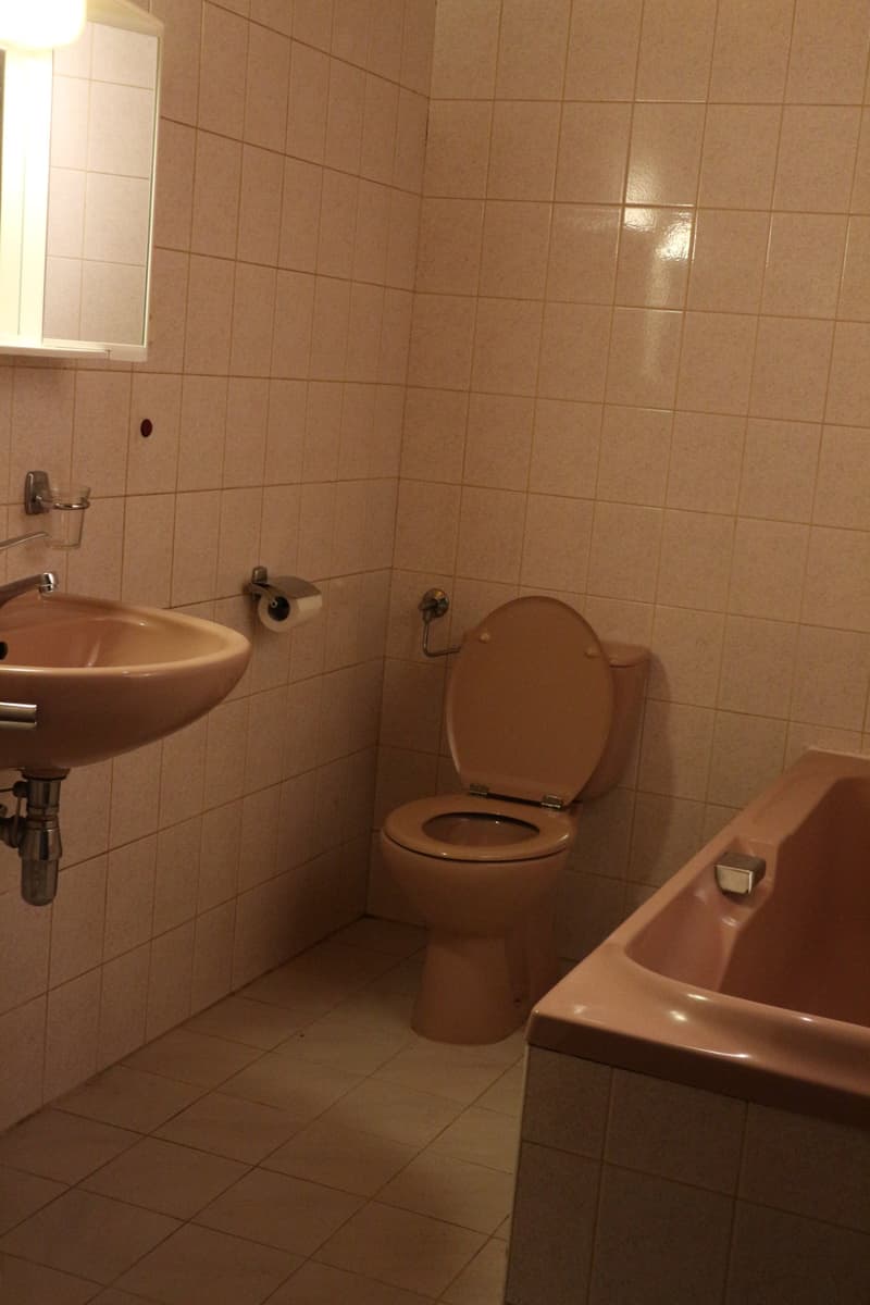Tiled bathroom with a sink, toilet, and a washing machine