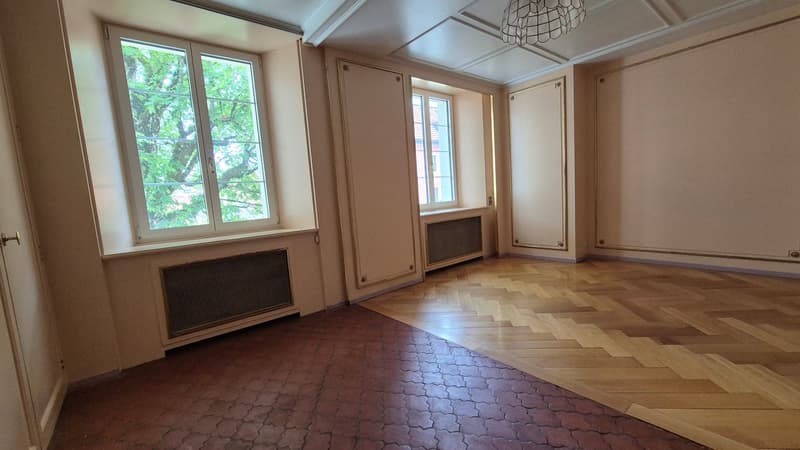 Empty room, wooden floor, two windows, radiators, white walls, chandelier ceiling
