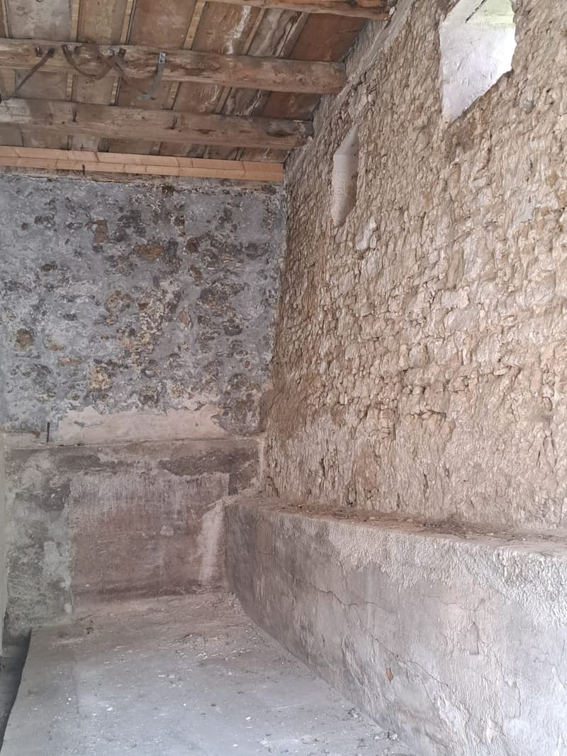 bare room with stone walls and wooden ceiling