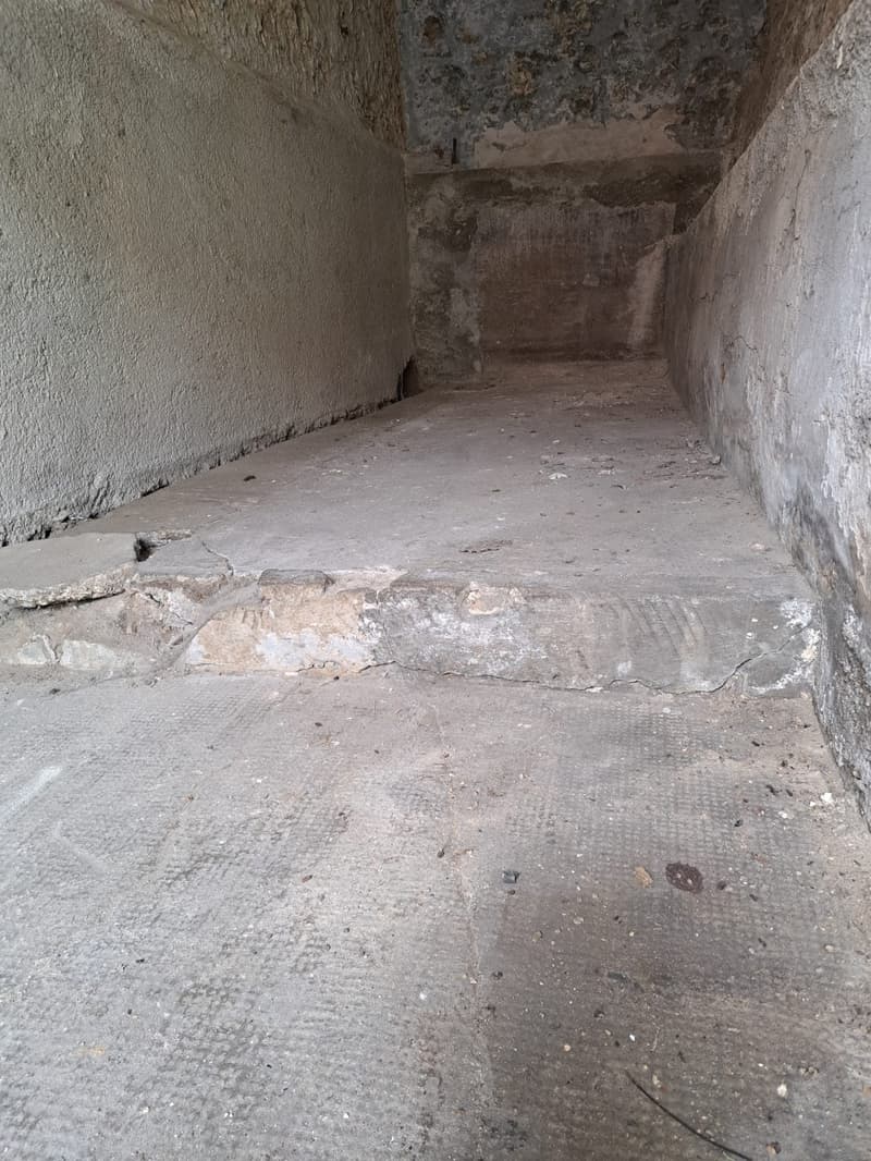 Empty room with concrete floor and damaged wall, no visible features